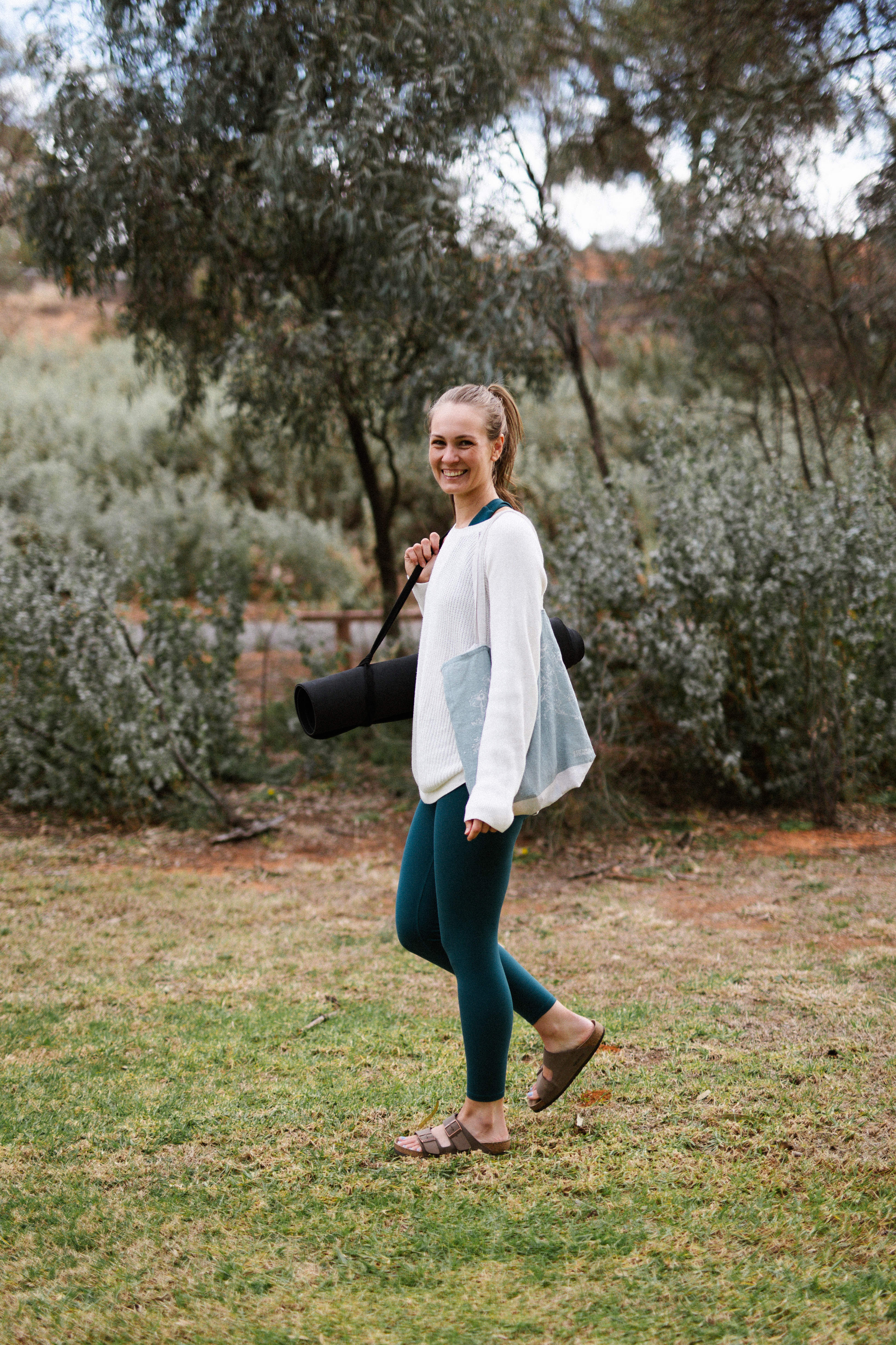 Andrea Dalton walking outdoors with a yoga mat